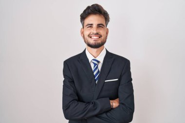 İş elbisesi ve kravat takan, kollarını kavuşturup kameraya gülümseyen İspanyol dövmeli genç adam. pozitif kişi. 