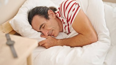 Orta yaşlı bir adam yatakta uzanıyor, yatak odasında uyuyor.
