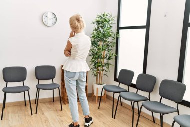 Sarışın genç kadın bekleme odasında geriye doğru bakıyor.