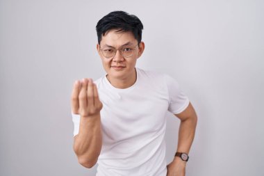 Beyaz arka planda duran Asyalı genç adam İtalyan jesti yapıyor. El ve parmakları kendinden emin bir ifadeyle. 