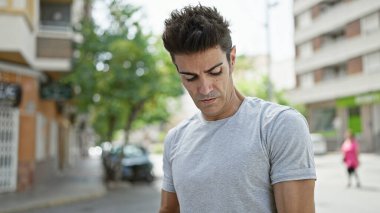 Genç İspanyol bir adam ciddi bir ifadeyle caddeye bakıyor.