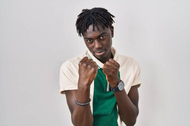 Afrikalı bir adam izole edilmiş arka planda duruyor. Yumruk savunma hareketleriyle dövüşmeye hazır kızgın ve üzgün bir yüz, sorundan korkuyor. 