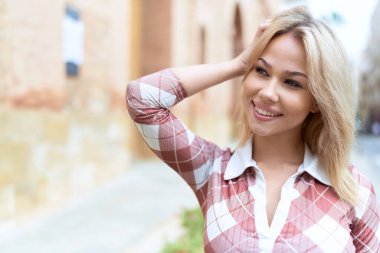 Sokakta kendine güvenen genç sarışın kadın gülümsüyor