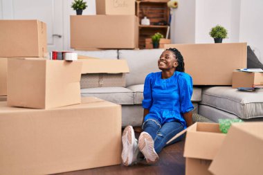 African american woman smiling confident sitting on floor at new home