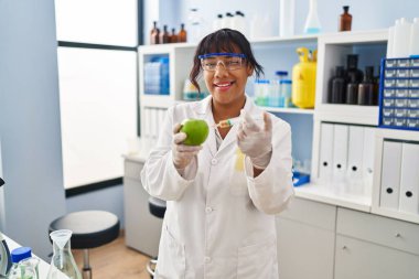 Elma kırparak bilim adamının laboratuvarında çalışan İspanyol kadın kameraya seksi bir ifadeyle, neşeli ve mutlu bir yüzle bakıyor.. 