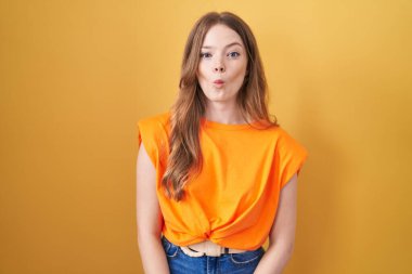 Sarı arka planda duran beyaz kadın dudaklarıyla balık suratı yapıyor. Çılgınca ve komik bir jest. Komik ifade. 