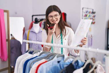 Terzide akıllı telefondan konuşan beyaz kadın elbise tasarımcısı.