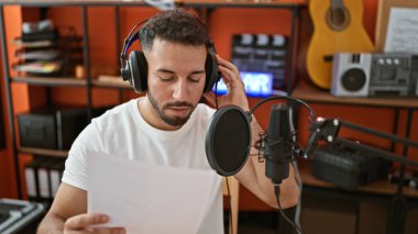 Genç Arap müzisyen müzik stüdyosunda şarkı söyleyen kulaklık takıyor.