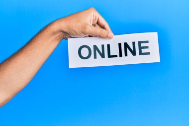 Hand of caucasian man holding paper with online word over isolated blue background