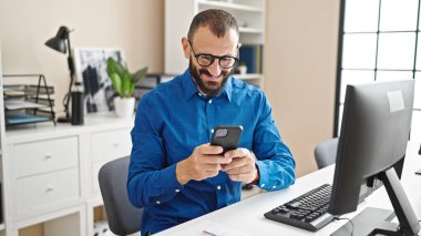 Ofiste bilgisayar ve akıllı telefon kullanan İspanyol bir iş adamı.