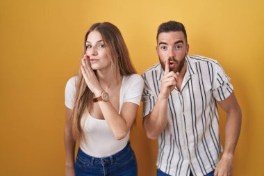 Sarı arka planda dikilen genç çift ağızlarının üstünde gizli dedikodular anlatıyor, kötü niyetli konuşmalar fısıldıyor. 
