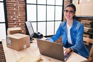 Genç ve güzel İspanyol kadın, iş kadını. Ofisteki evraklarda dizüstü bilgisayar kullanıyor.