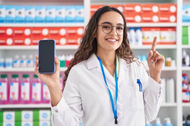 Eczanede çalışan Latin kökenli genç bir kadın akıllı telefon ekranı gösterip kahkahalar atıyor.. 