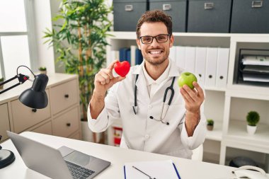 Diyet kliniğinde çalışan genç İspanyol adam yüzünde mutlu ve havalı bir gülümsemeyle gülümsüyor. diş gösterme. 