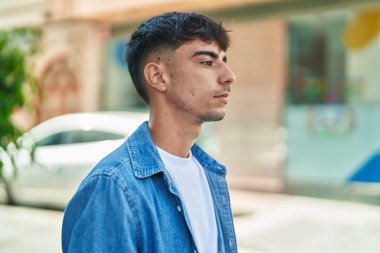 Latin kökenli genç adam ciddi bir ifadeyle sokağa bakıyor.