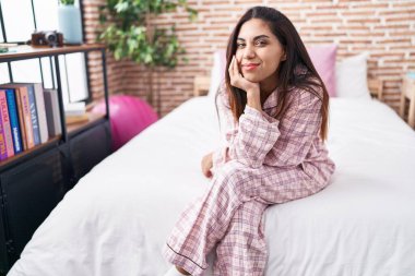 Young beautiful arab woman smiling confident sitting on bed at bedroom
