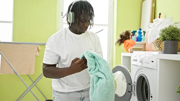 African american man listening to music washing clothes at laundry room