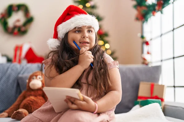 Size Hispanic Girl Thinking Write Sitting Sofa Christmas Tree Home — Foto de Stock