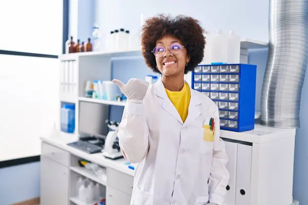 Joven Afroamericana Mujer Trabajando Laboratorio Científico Señalando Pulgar Hacia Lado —  Fotos de Stock