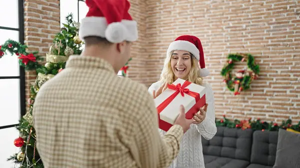 Man and woman couple surprise with christmas gift at home