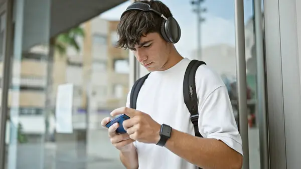 大学でビデオゲームをするバックパックを身に着けている若いヒスパニックティーンエイジャーの学生 — ストック写真