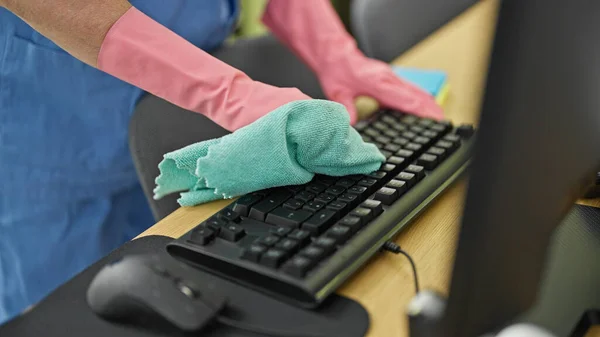 Middle age woman professional cleaner cleaning keyboard at office