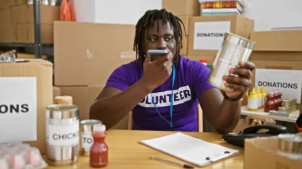 African american man volunteer sending voice message by smartphone at charity center
