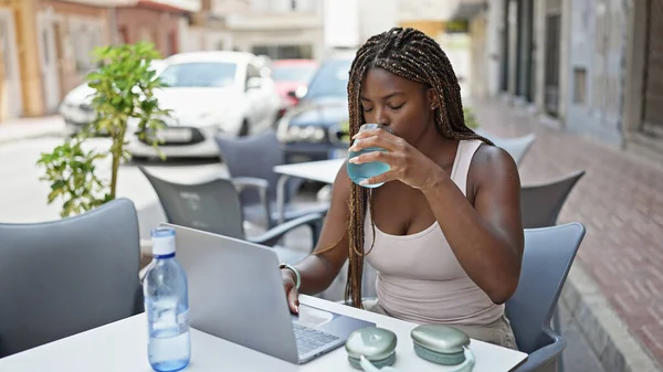 Mujer Afroamericana Bebiendo Vaso Agua Usando Portátil Terraza Cafetería — Foto de Stock