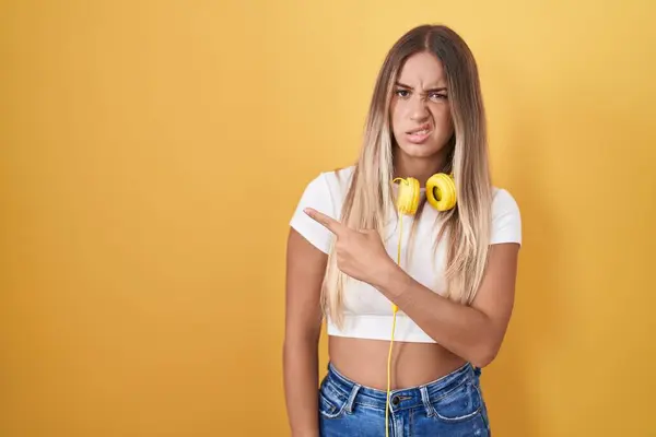 Young Blonde Woman Standing Yellow Background Wearing Headphones Pointing Aside — Stock Photo, Image