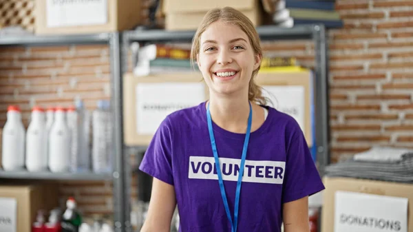 Νεαρή Ξανθιά Γυναίκα Εθελοντής Χαμογελώντας Αυτοπεποίθηση Στέκεται Στο Κέντρο Φιλανθρωπίας — Φωτογραφία Αρχείου
