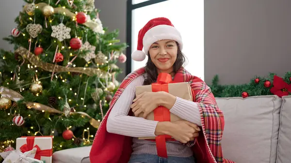 Νέα Όμορφη Ισπανόφωνη Γυναίκα Κρατώντας Χριστουγεννιάτικο Δώρο Κάθεται Στον Καναπέ — Φωτογραφία Αρχείου