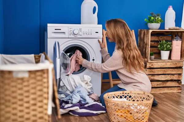 Young woman washing clothes at laundry room