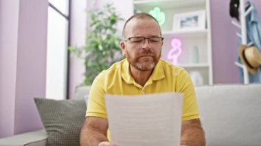 Yakışıklı, orta yaşlı, beyaz bir adam akıllı bir belgeyi okumaktan zevk alır. Evdeki kanepede güven içinde otururken mutlu bir gülümseme sakallı yüzünü aydınlatır..