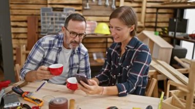 İki neşeli marangoz marangoz, marangozhanede kahve molası veriyorlar cep telefonu mesajları üzerinden canlı bir sohbete dalmışlar.