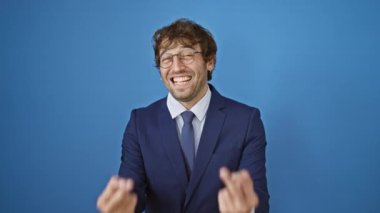 Young man wearing business suit showing middle finger doing fuck you bad expression, provocation and rude attitude. screaming excited over isolated blue background