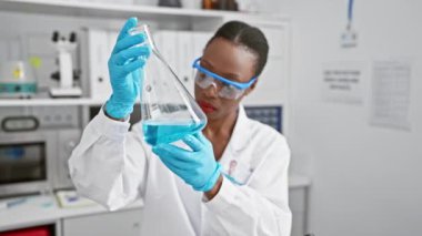 Çalışkan ve güzel Afrikalı Amerikalı bilim adamı yüksek teknolojili bir laboratuarda test tüpünü analiz ediyor.