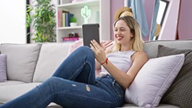 Tablette video çağrısı olan kadın, el sallıyor.