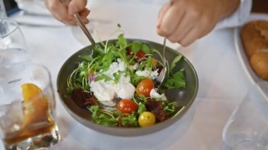 Restoranda burrata salatası hazırlayan genç bir kadın.