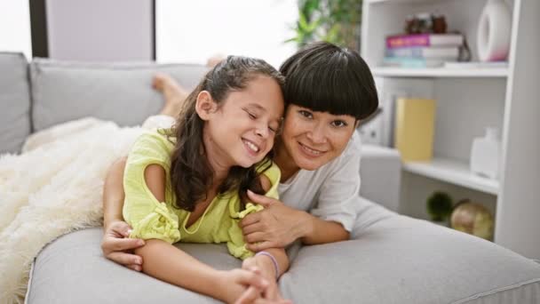 自信的母亲和女儿相互拥抱 微笑着离去 躺在客厅的沙发上 流露出积极的生活方式和爱心 — 图库视频影像