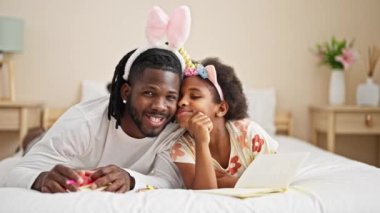 Afrika kökenli Amerikalı baba ve kızı, yatakta yatıp gülümseyerek tuhaf bir diyabet giyiyorlar.