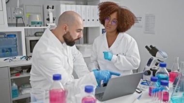İki ciddi bilim adamı birlikte konuşuyor. Kapalı laboratuarda dizüstü bilgisayarda araştırma sezgileri keşfediyorlar.