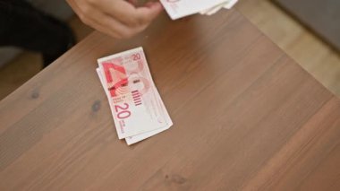 Kanepede oturan genç bir adam, para sayıyor - İsrail ekonomisinde finansal başarının kapalı bir görüntüsü.
