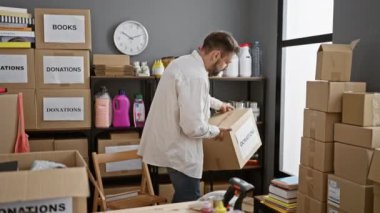 Bir hayır kurumunda gönüllü olarak çalışan, cemiyet desteği için bağış paketleri tutan, ciddi yüzlü, genç bir İspanyol 'un samimi portresi.