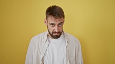 Serin ve sıradan İspanyol asıllı, ciddi, rahat bir ifade takınan, sakallı yakışıklı, izole edilmiş sarı duvar arkasında tek başına duran genç bir adam. Yetişkin erkek portresi.