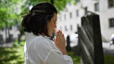 Güzel, genç, İspanyol bir kadın mezarlıkta dua ediyor ve yas tutuyor.