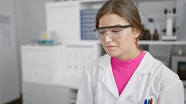 Çekici genç İspanyol bilim kadını, kendine güveni ve güzelliğiyle ışıldıyor, laboratuvarda çalışıyor, güvenlik gözlüğü takıyor..
