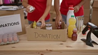 Genç bir adam ve güzel bir kadın bağışlamak için yardım merkezinde ürünleri bir araya getiriyorlar.