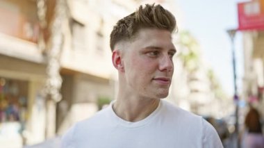 Kendinden emin, sportif görünümlü beyaz bir adam şehrin açık alanındaki hareketli bir caddede gülümseyerek pozitiflik, neşe ve rahat bir hava yayarken yakalandı..