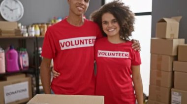 Gülümseyen adam ve kadın gönüllüler, birlikte çalışıyorlar, yardım merkezinin kalbinde güzel bir anı paylaşıyorlar, üniformalarla gururla duruyorlar, toplum birliğini teşvik ediyorlar.