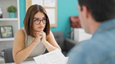 Ofisteki masada oturan iki işçi ve kadın evrak okuyorlar.